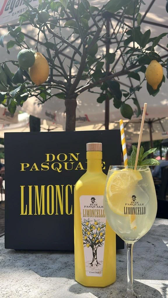 Glas Don Pasquale Limoncello Spritz mit Eis, Zitrone und Minze neben einer Limoncello Flasche im Capablanca Siegburg